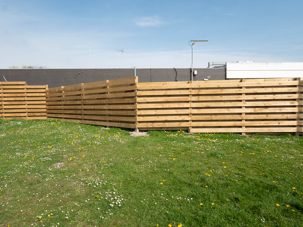 Horizontal slatted timber fencing installed along a site boundary by SKI Groundworks
