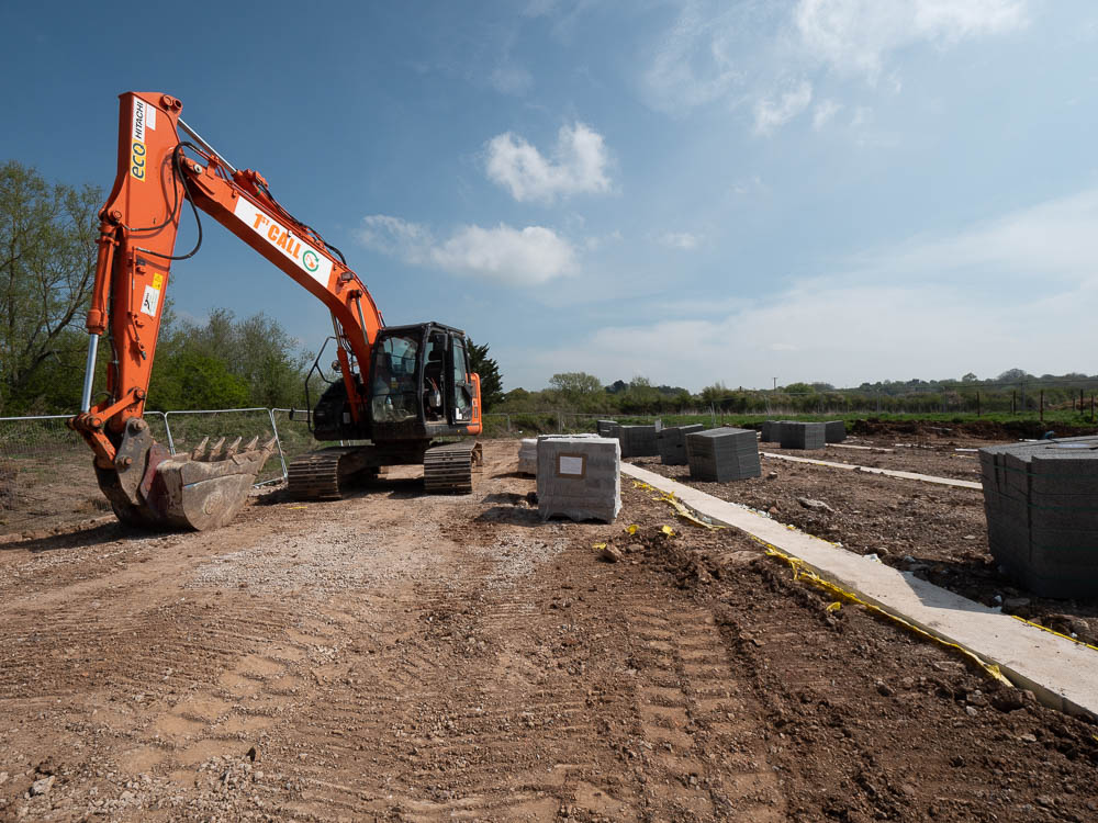 Tracked excavator preparing new-build housing plots on a groundworks site