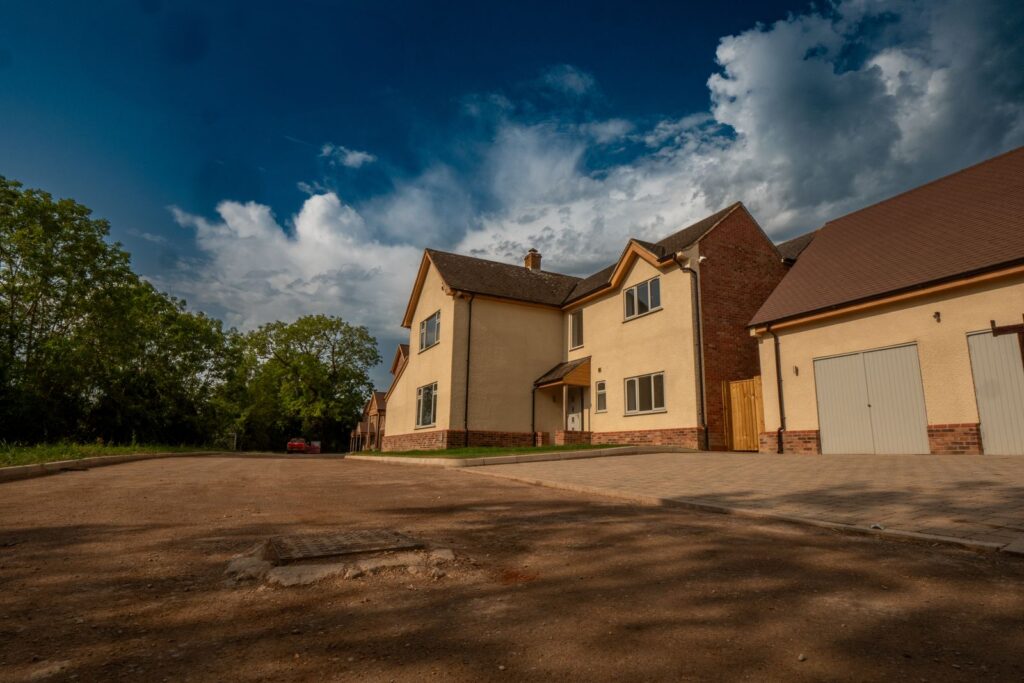 Compacted road sub-base and drainage access prepared alongside new homes in Gloucestershire.
