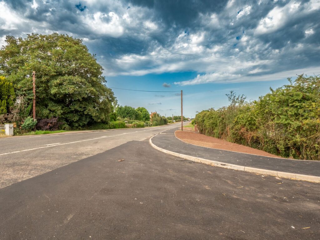 Kerbs and edgings work in Gloucestershire with a curved kerb line, tarmac footway and prepared verge.
