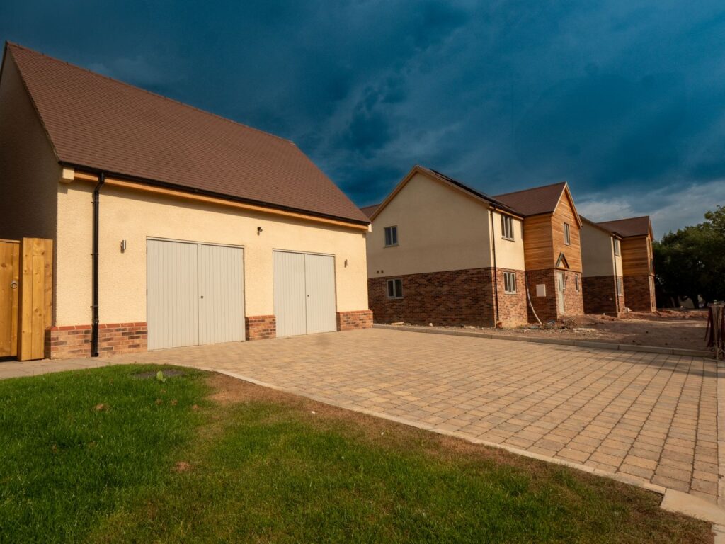 Broad block paving provides a finished driveway surface between new homes in Gloucestershire.