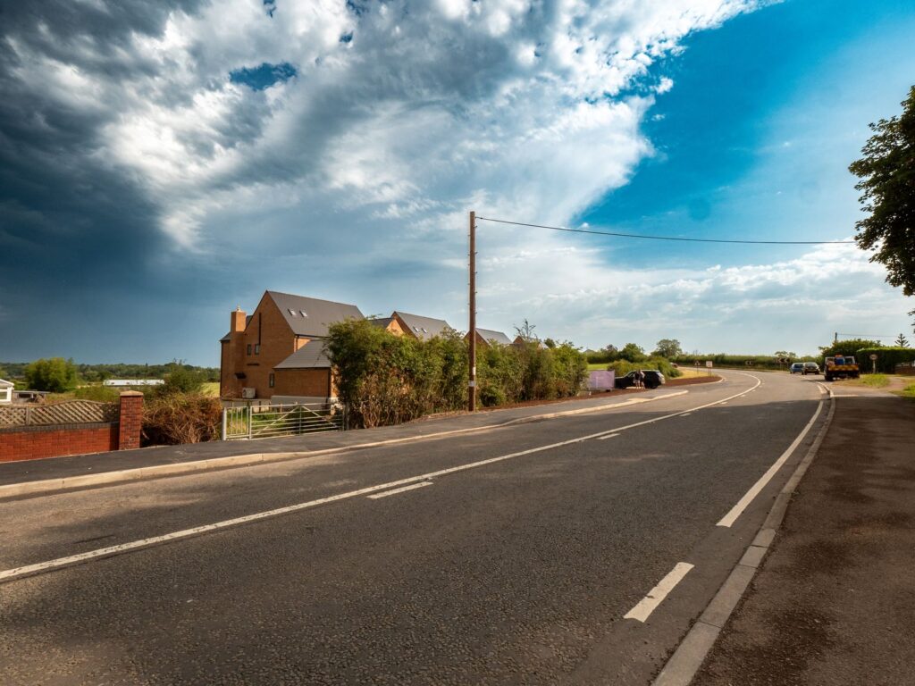 Roads and sewers work in Gloucestershire with tarmac footways, kerbs, road markings and a development frontage.