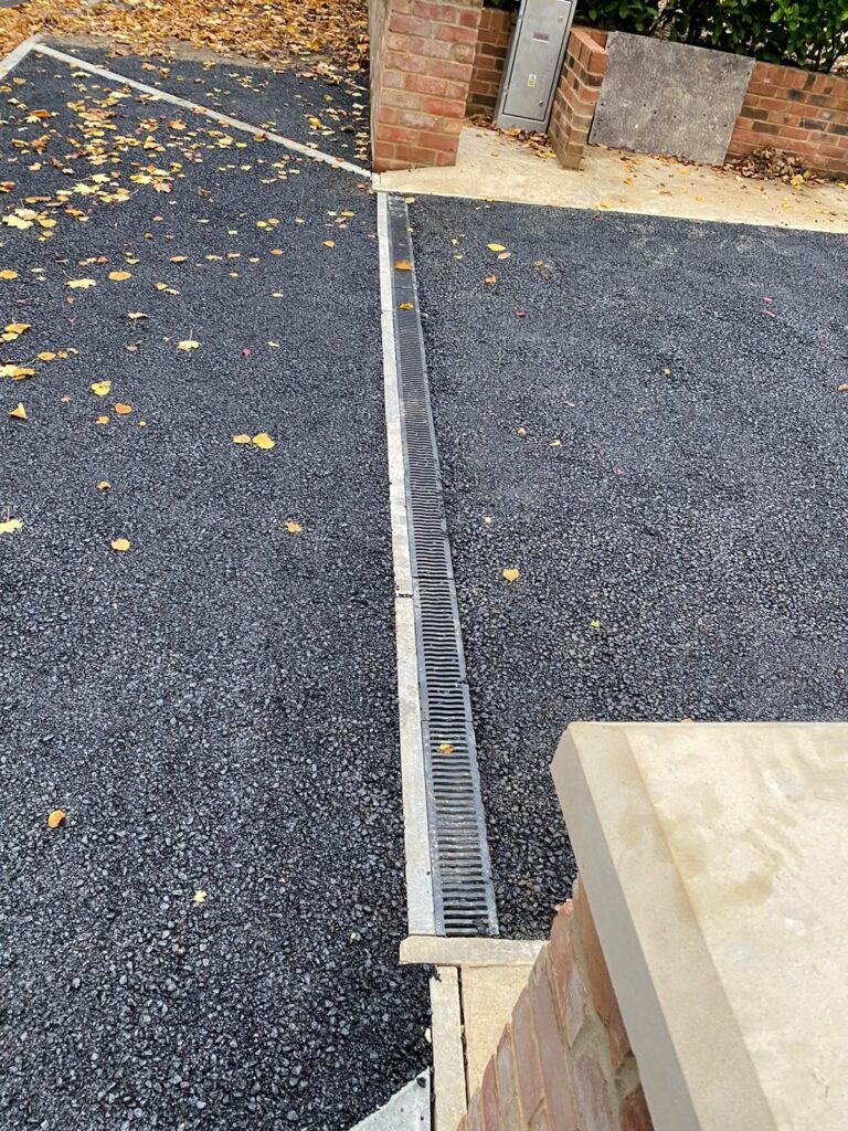 Channel drain installed across a tarmac driveway.