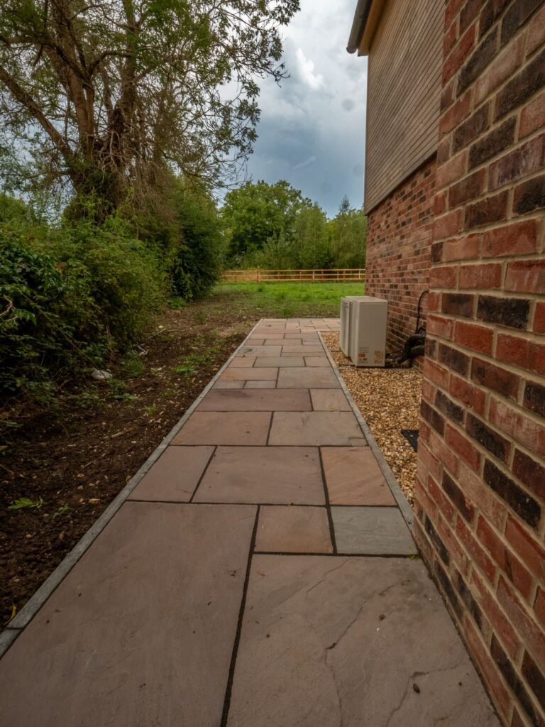 An edged sandstone garden path provides durable paths and paving beside a residential property in Gloucester.
