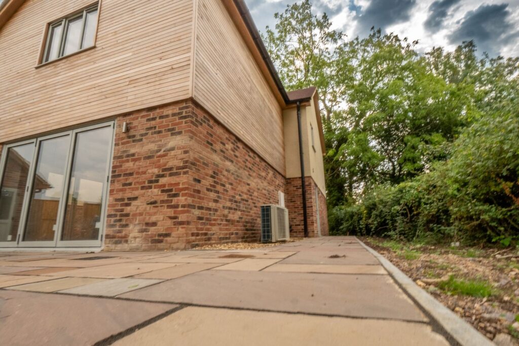 Finished sandstone garden patio around a new-build home in Gloucestershire.