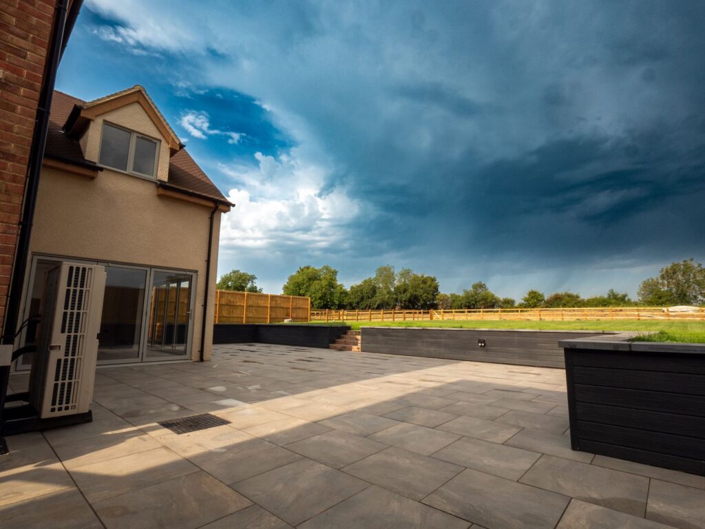 Finished porcelain garden patio with raised borders at a Gloucestershire home.