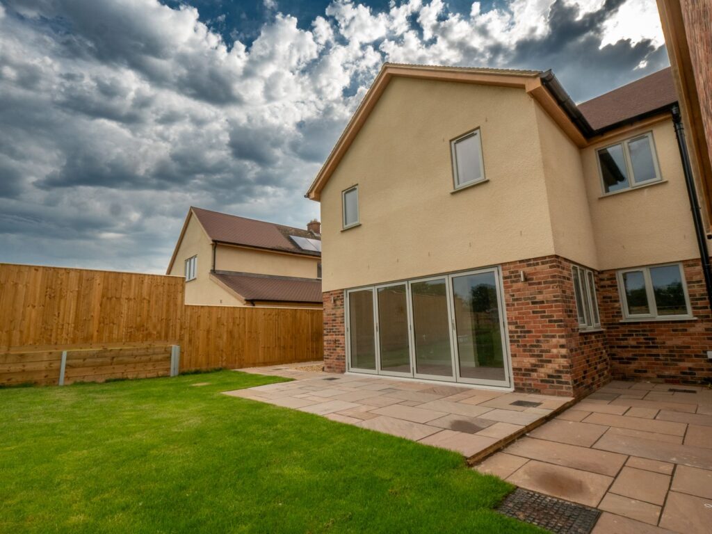 Completed sandstone garden patio paving meets the lawn to form a usable space at this Gloucester home.