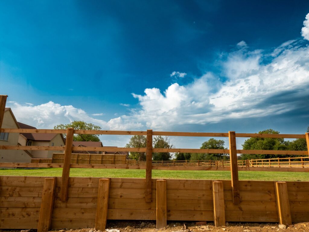 A timber boundary fence with retaining boards securing a residential development plot in Gloucestershire.