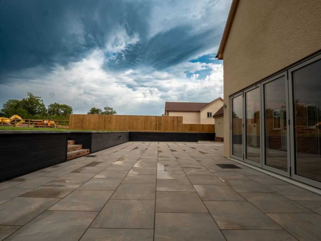 Large grey porcelain garden patio with raised planters installed in Gloucester.
