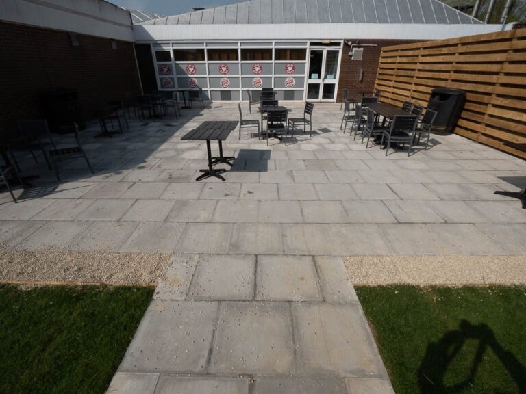 Slab-paved outdoor seating area with tables at Moto Leigh Delamere Services.
