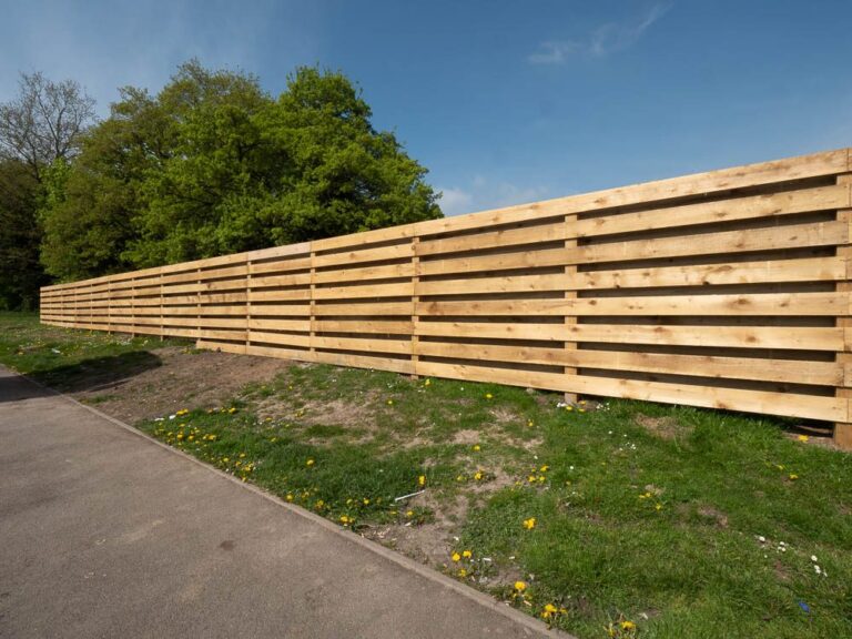 Long run of timber screen fencing beside a footpath at Moto Leigh Delamere Services.